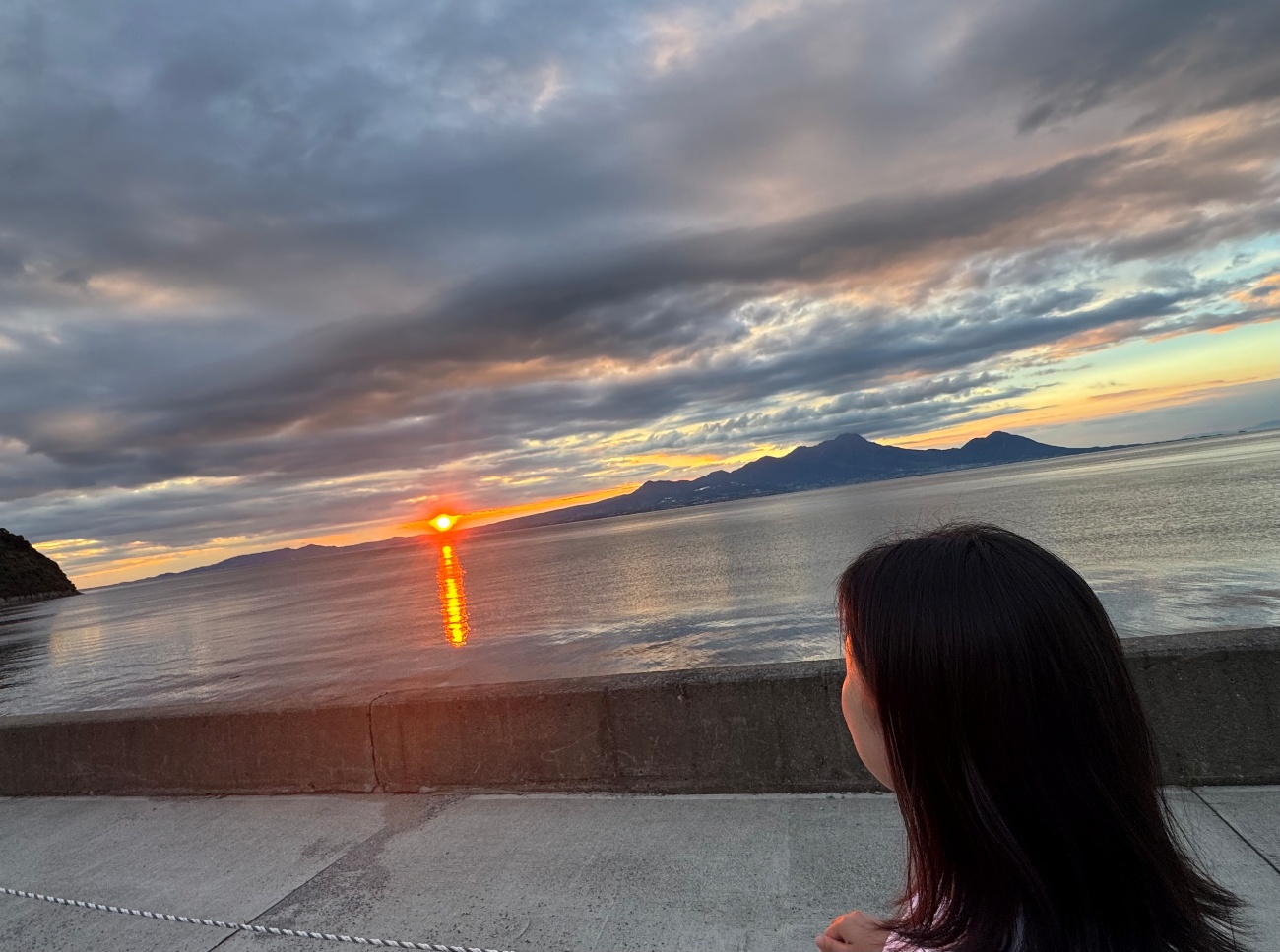 M.A. looking out over the sea at sunset